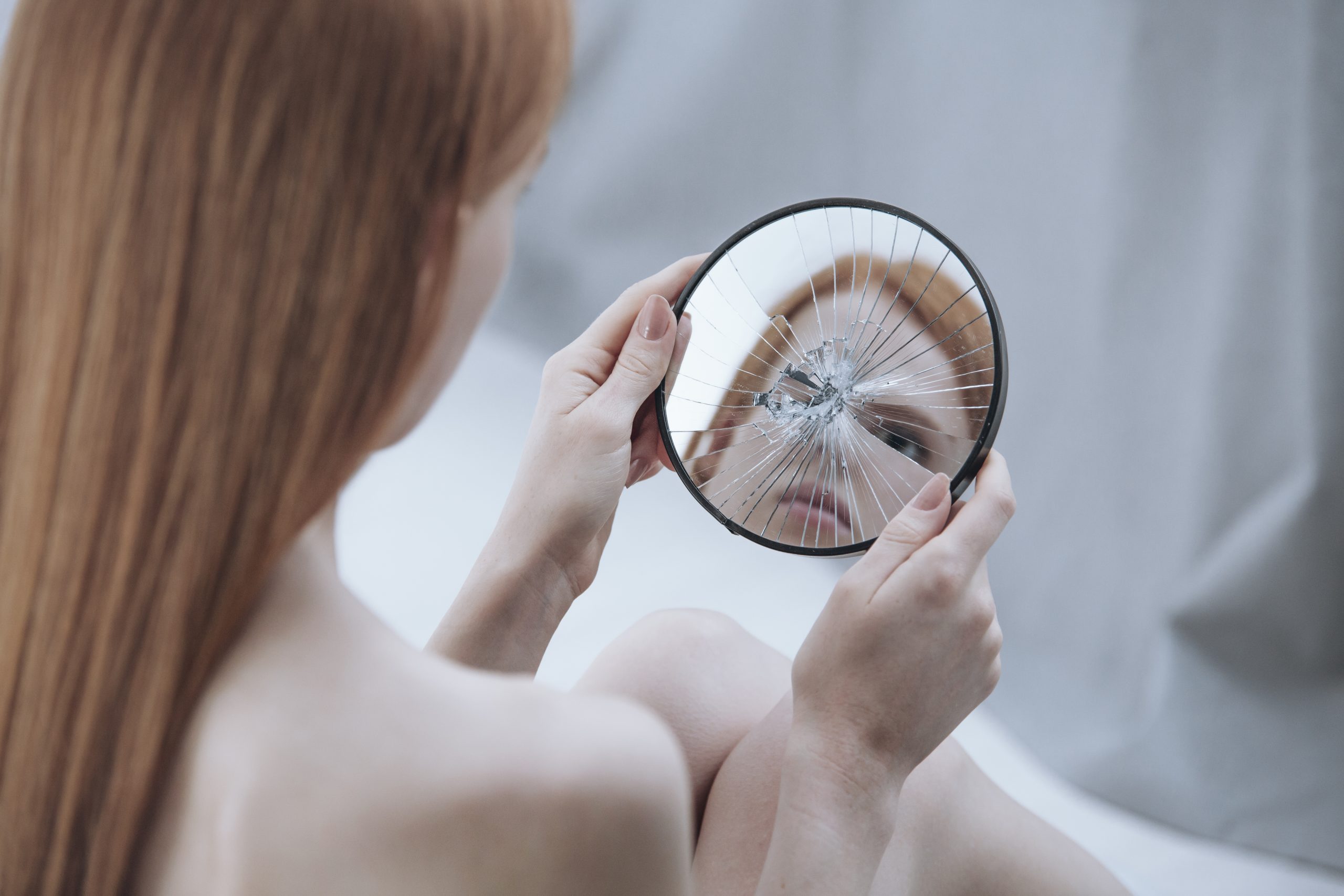Distorted,Reflection,Of,A,Woman,In,A,Small,,Broken,Mirror
