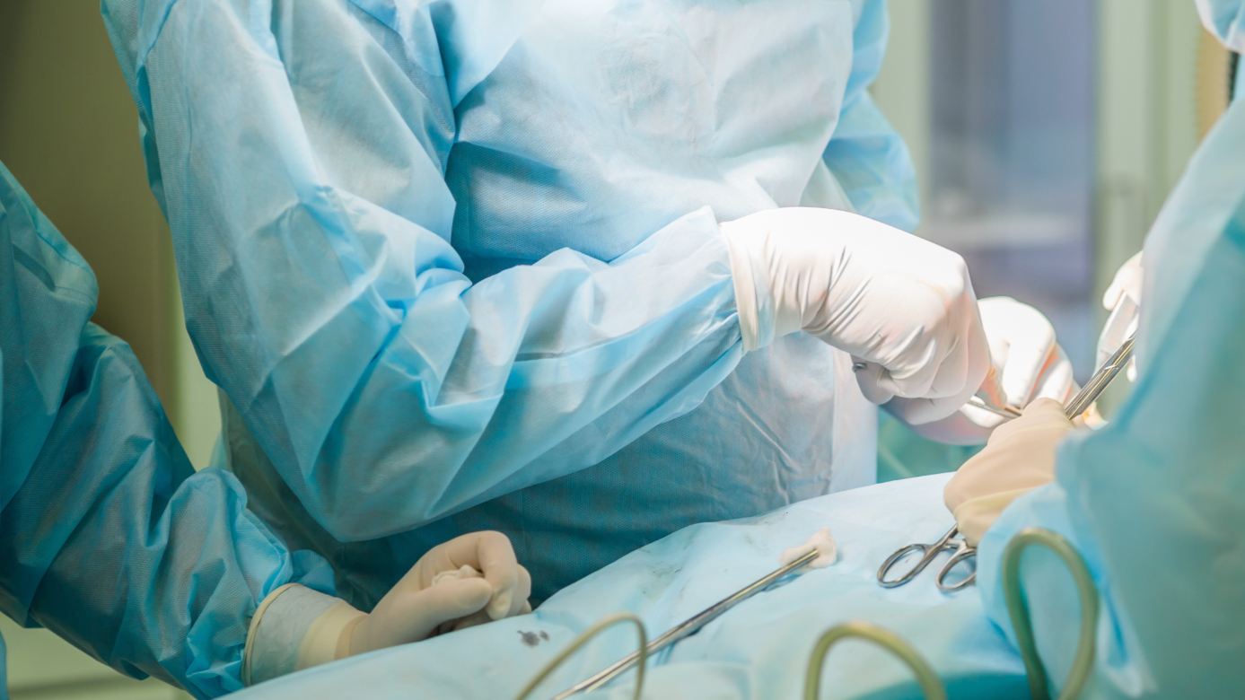 Surgical team performing cosmetic surgery in hospital operating room. Surgeon working on a patient. Breast augmentation, enlargement, enhancement at medical clinic. Mammaplasty