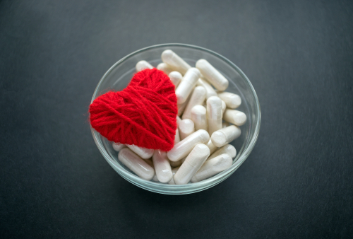 White,Veg,Capsules,And,Red,Thread,Heart,In,Glass,Bowl