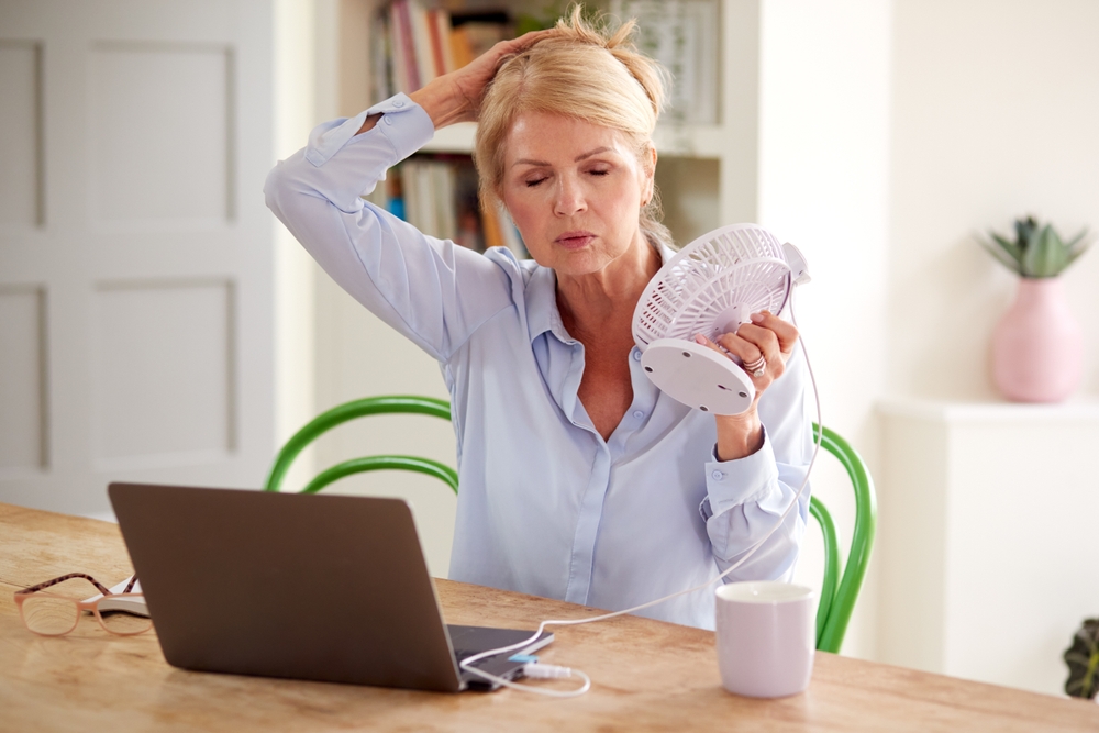 Menopausal,Mature,Woman,Having,Hot,Flush,At,Home,Cooling,Herself