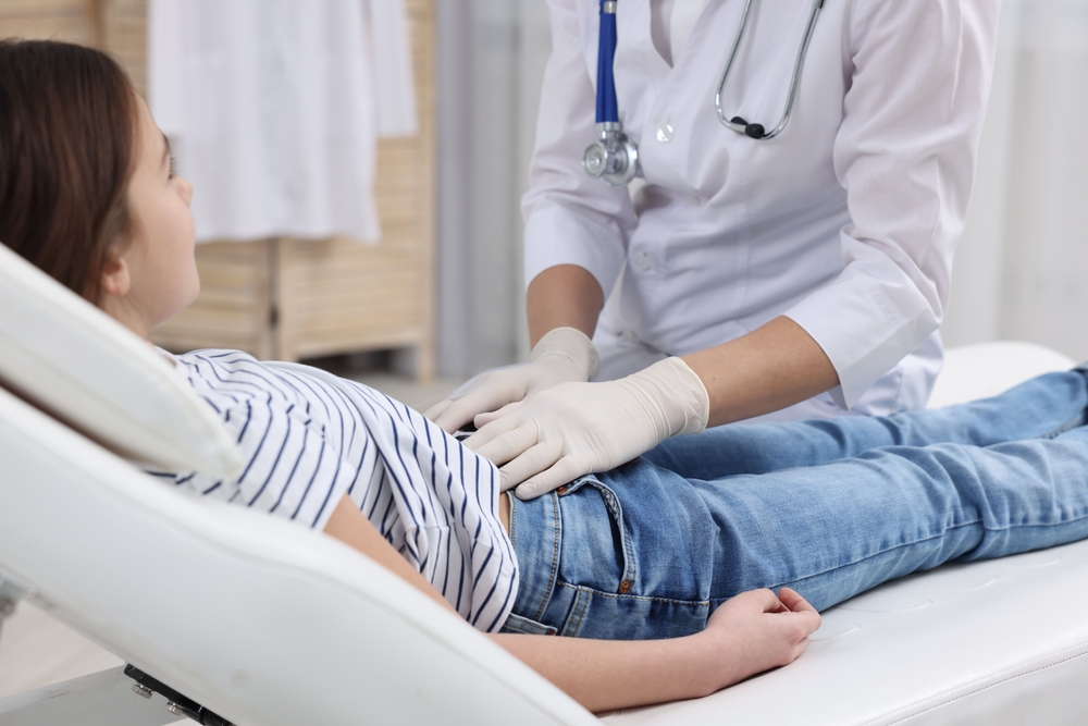 Gastroenterologist,Examining,Girl,With,Stomach,Ache,On,Couch,In,Clinic,