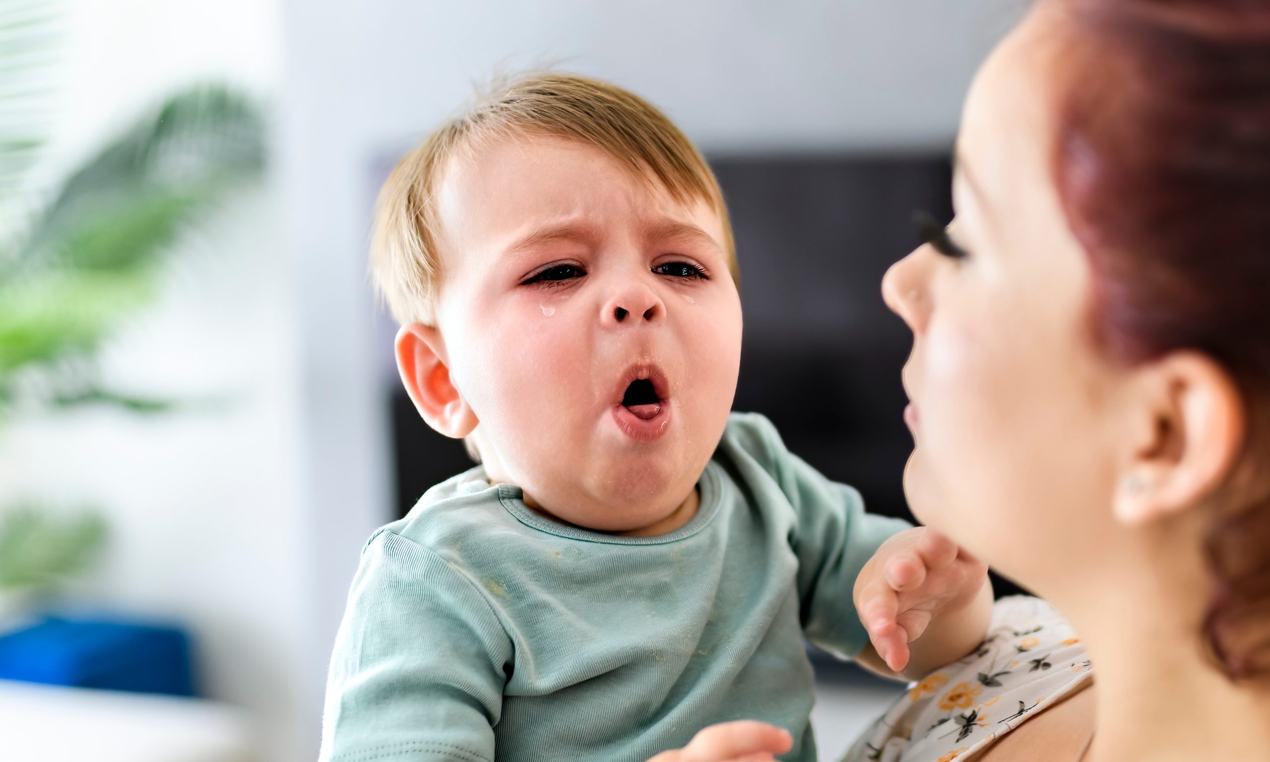 A mother holding child baby on the living room. The baby is sick having some cough