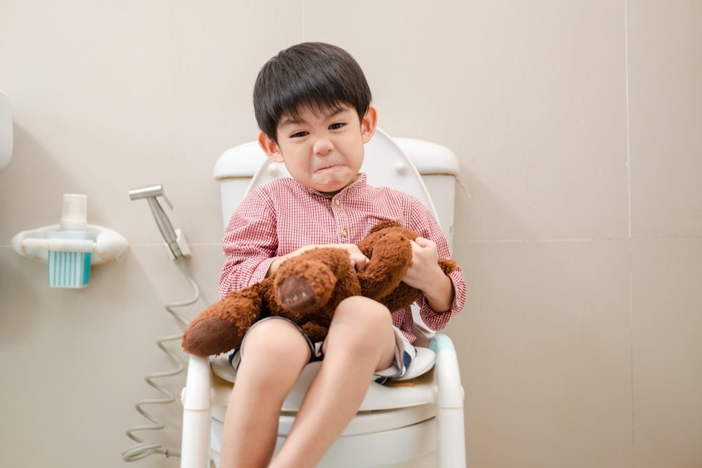 Asian,Boy,Sitting,On,The,Toilet,Bowl,In,Hand,Holding